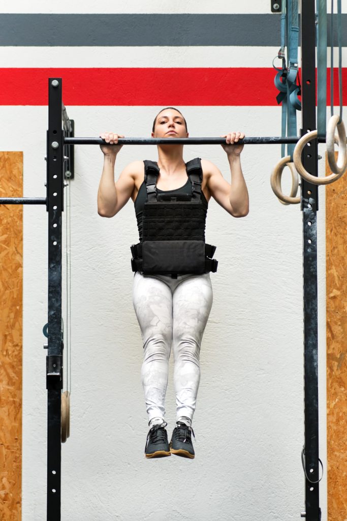 Kvinde som laver pull-ups med vægtvest 30 kg.